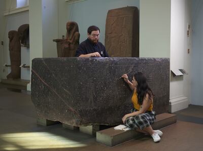 Senior Conservator Stephanie Vasiliou and Conservation Student Shoun Obana clean 'The Enchanted Basin', a large black granite sarcophagus with hieroglyphs from about 600 BCE, in the Egyptian Sculpture Gallery at the British Museum.