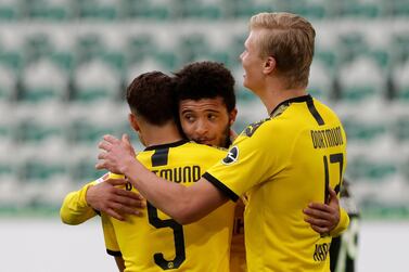 Dortmund's Achraf Hakimi, left, celebrates with Jadon Sancho and Erling Haaland, right, after scoring his side's second goal during the German Bundesliga soccer match between VfL Wolfsburg and Borussia Dortmund in Wolfsburg, Germany, Saturday, May 23, 2020. The German Bundesliga is the world's first major soccer league to resume after a two-month suspension because of the coronavirus pandemic. (AP Photo/Michael Sohn, Pool)