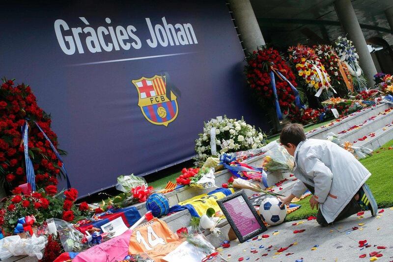 A FC Barcelona fan puts ball on the ground as he pays tribute to late Dutch football star Johan Cruyff in a special condolence area set up at Camp Nou stadium, in Barcelona on March 27, 2016. Cruyff, one of the greatest footballers of all time who dazzled with his artistry, died on March 24, 2016 at the age of 68 after losing a battle with lung cancer, prompting an avalanche of tributes from around the sports world. / AFP / PAU BARRENA