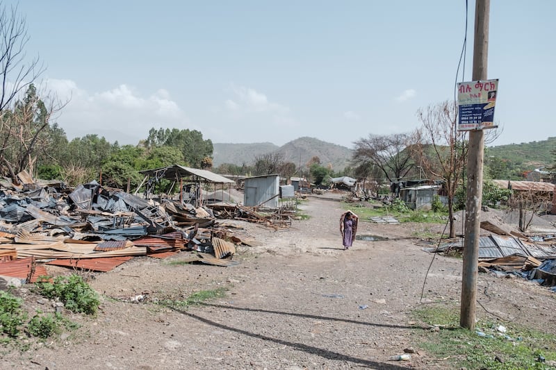 A woman walks among the remains of a destroyed factory in Ataye, Ethiopia, where more than 100 civilians died in a recent flare-up of violence.