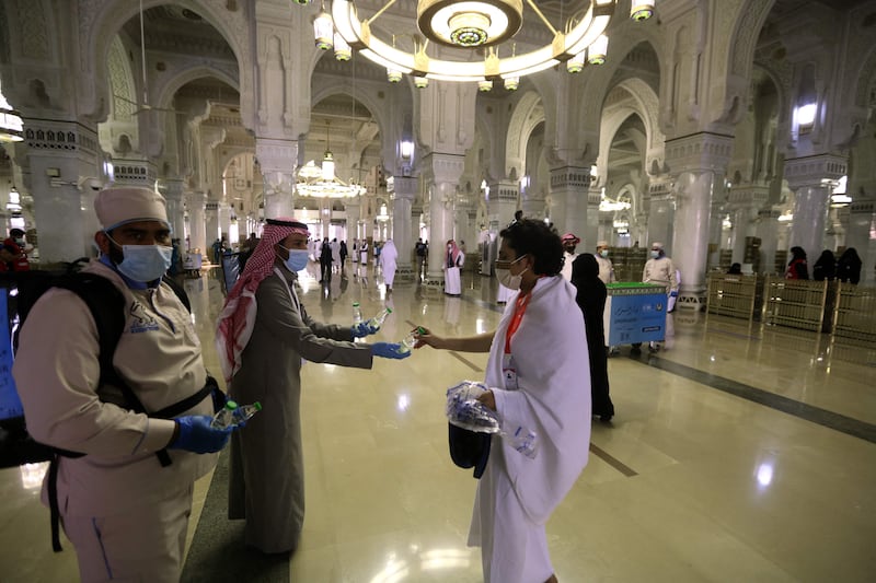 A man hands a bottle of water to a pilgrim at the Grand Mosque.