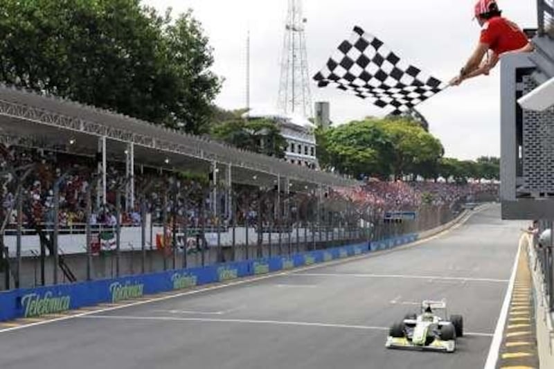 Felipe Massa waves the checkered flag as Jenson Button goes past  the end of the Brazilian GP at Interlagos last year.