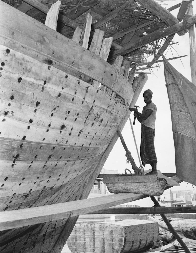 A man works on a large wooden boat at a shipyard in Manama in about 1950.