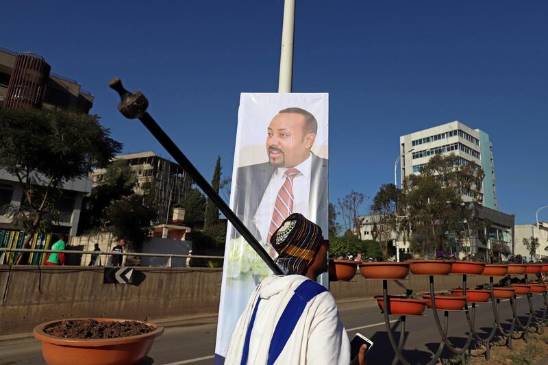 A man dressed in a traditional Oromo costume walks past a banner with Ethiopia's Prime Minister Abiy Ahmed during celebrations to welcome him upon the return from Oslo, where he received the Nobel Peace Prize, in Addis Ababa, Ethiopia, December 12, 2019. REUTERS/Tiksa Negeri
