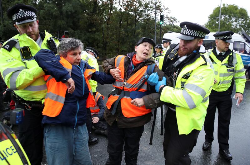 Police officers detain Insulate Britain activists. Reuters