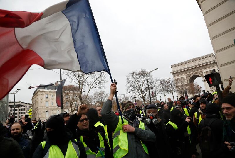 Demonstrators wearing yellow vests march down the Champs Elysees holding the French tricolor in Paris. AP Photo