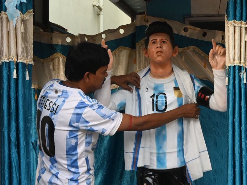Argentina football fan Shib Shankar Patra adjusts a statue of Lionel Messi beside his tea stall, painted in the team’s colours, in Ichhapur, north of Kolkata. AFP
