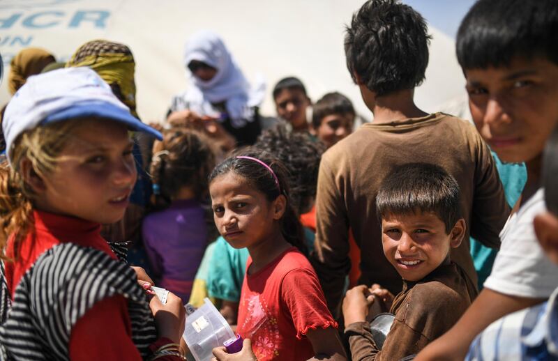 Displaced Syrian children who fled the countryside surrounding ISIL's Raqqa stronghold wait for food to be distributed at a temporary camp in the village of Ain Issa on July 11, 2017. Bulent Kilic / AFP