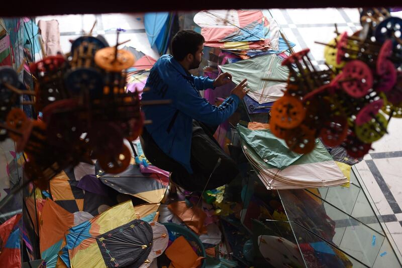 A kite vendor cuts tissue paper as he makes a kite in a shop in Shor Bazaar in Kabul.