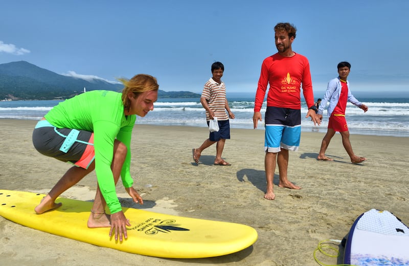 A tourist learns the basics of surfing on China Beach.