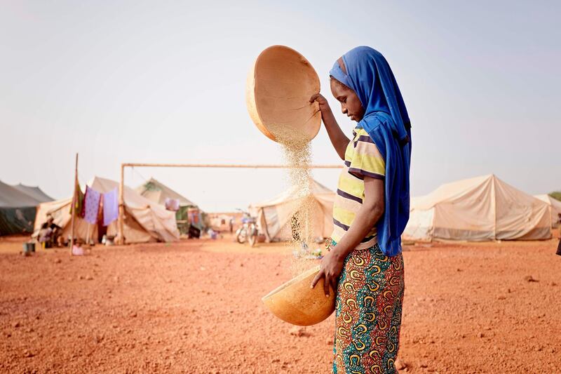 A little girl is seen while she's sifting the mile with two bowls in a camp in the town of Sevare for internally displaced people from the ongoing conflict in Mali, on February 28, 2020.  In total 151 households and 712 individuals have fled their villages in central Mali and found a shelter in the camp. AFP
