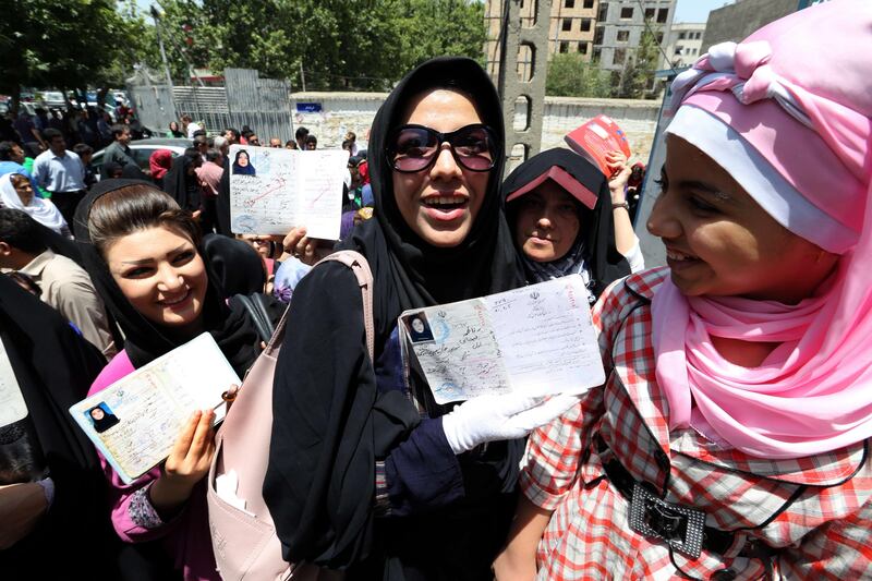 Iranian women show their documents as they queue to vote in the first round of the presidential election at a polling station in Tehran on June 14, 2013. Iranians are voting to choose a new president in an election the reformists hope their sole candidate will win in the face of divided conservative ranks, four years after the disputed re-election of Mahmoud Ahmadinejad. AFP PHOTO/ATTA KENARE
 *** Local Caption ***  341280-01-08.jpg