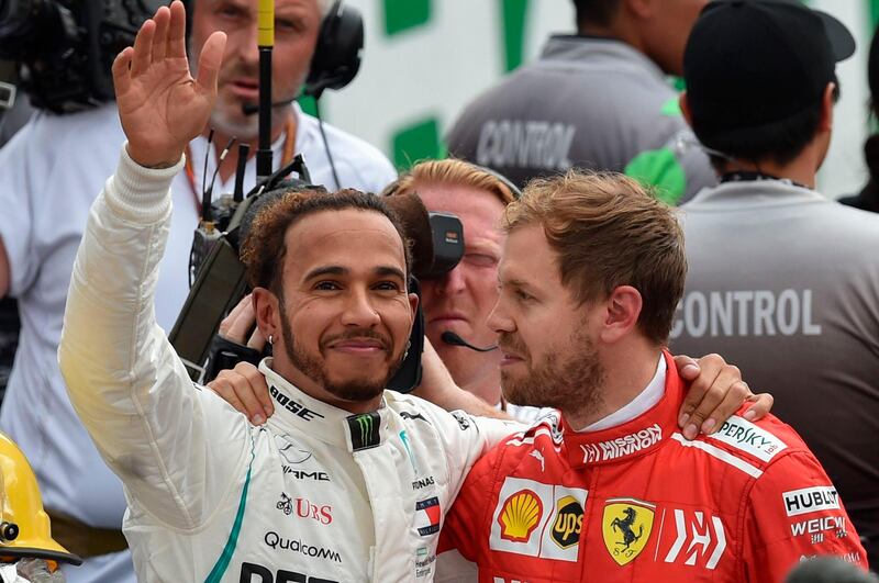 TOPSHOT - Mercedes' British driver Lewis Hamilton (L) waves at the crowd as he hugs Ferrari's German driver Sebastian Vettel, after winning his fifth drivers' title after the F1 Mexico Grand Prix at the Hermanos Rodriguez circuit in Mexico City on October 28, 2018. Lewis Hamilton became only the third Formula One driver in history to capture a fifth world title on Sunday as Max Verstappen won the Mexican Grand Prix. / AFP / Rodrigo ARANGUA
