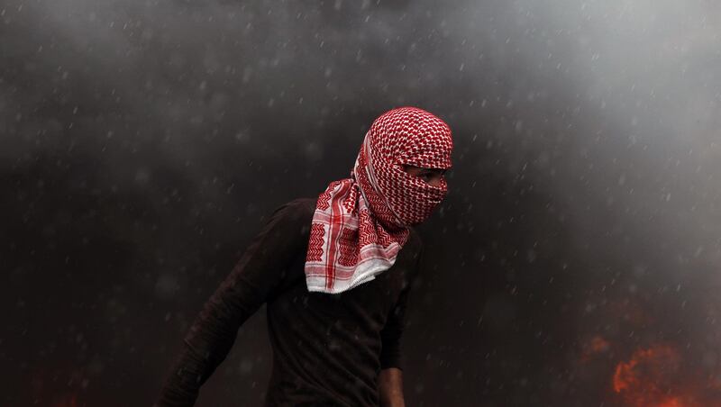 A Palestinian protester seeks cover during clashes with Israeli forces intervening with tear gas during a protest against Israel in the West Bank City of Ramallah. EPA