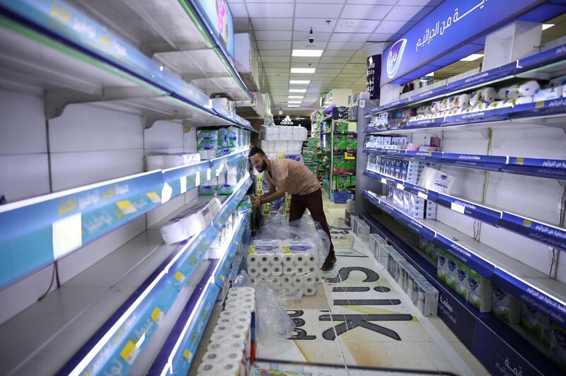 A worker arranges goods on an empty shelve in a mall amid concerns over the coronavirus (COVID-19) spread, in Amman Jordan. REUTERS