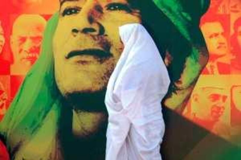 A Libyan woman walks past a picture of Libyan leader Moamer Kadhafi in Tripoli on August 30, 2009 as celebration to mark the 40th anniversary of Kadhafi coming to power get under way. Libya is marking on September 1 the anniversary of the coup against the monarchy that brought Kadhafi to power on September 1, 1969. AFP PHOTO/AMMAR ABD RABBO *** Local Caption ***  697916-01-08.jpg