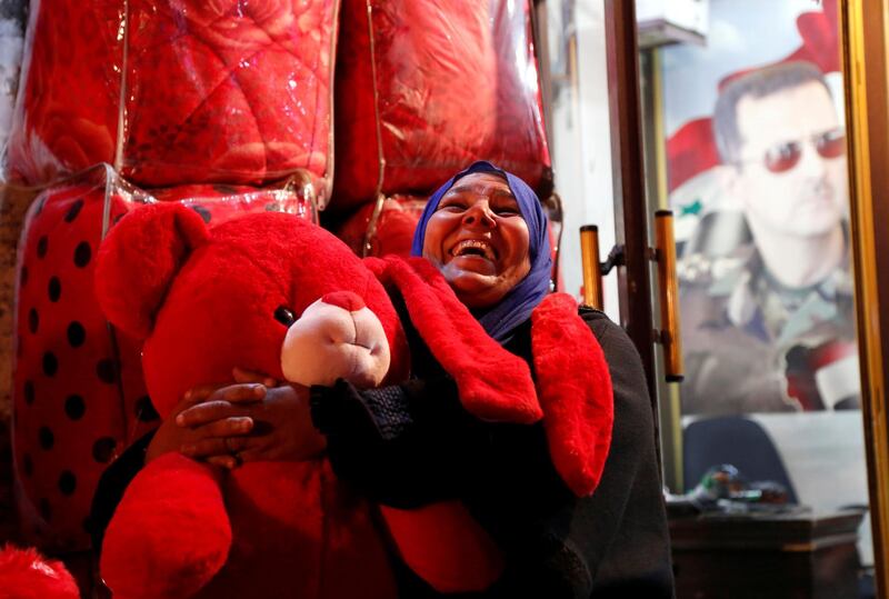 A woman reacts as she holds a red teddy bear for sale for Valentine's Day in Damascus, Syria. Reuters