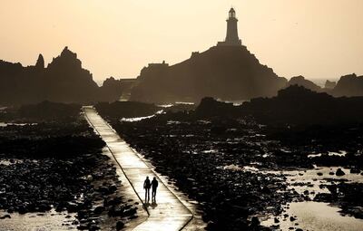 JERSEY, UNITED KINGDOM - MARCH 01: A couple walk on the causeway leading to the Corbiere lighthouse on March 1, 2008 in Jersey, Channel Islands.  Britain's most southerly island - Jersey is located 100 miles  south of mainland Britain and 14 miles from the coast of France. Jersey measures nine miles by five and is one of The Channel Islands which are British Crown Dependencies but are not part of the United Kingdom. Tourism, banking and finance are the mainstays of the economy.  (Photo by Peter Macdiarmid/Getty Images)
