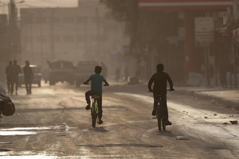 Boys ride on bicycles in the border town of Tal Abyad, Syria. REUTERS