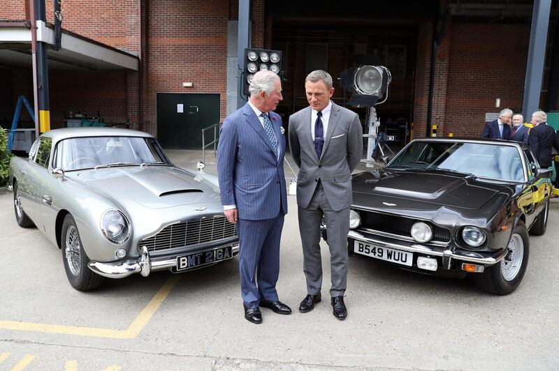 The royal poses with Daniel Craig in front of two Aston Martins that will appear in the films. Getty Images
