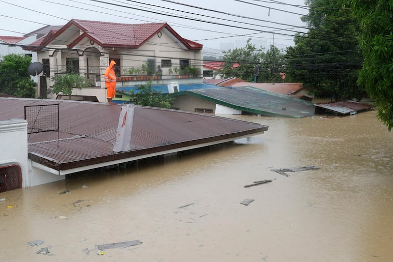 A man stands on the a roof as floods continue to rise in Marikina. AP Photo