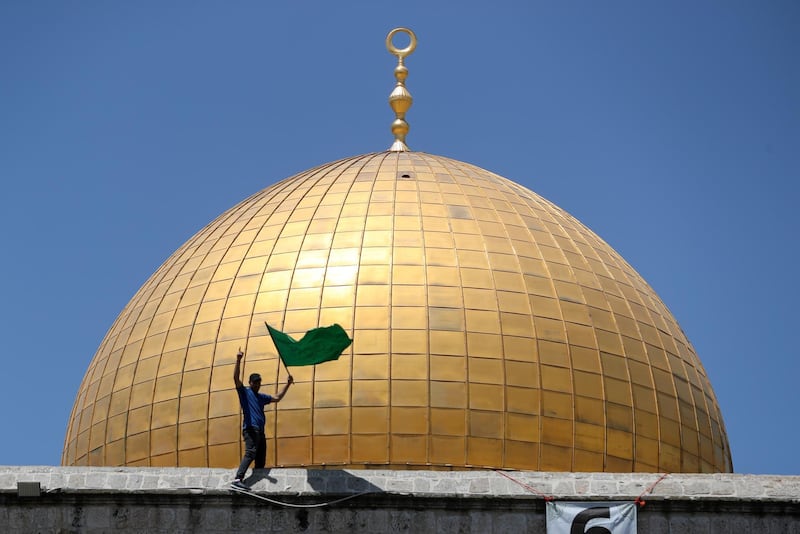 A man holds a Hamas flag while standing on the Dome of the Rock in Jerusalem. Reuters