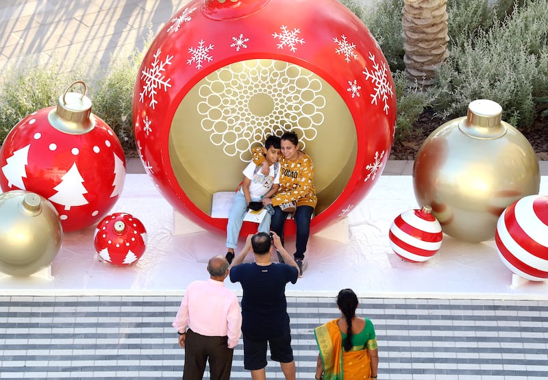 A family takes pictures in giant Christmas decorations at Expo 2020 in Dubai. Chris Whiteoak/ The National
