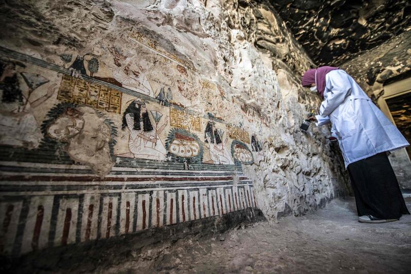An archaeologist brushes the painted walls of the tomb. AFP