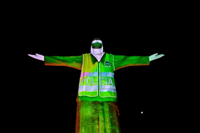 The image of a police officer is projected on the statue of Cristo Rey monument next to moon in Cali, Colombia, during celebrations for the 484th anniversary of the city, amid the coronavirus pandemic.  AFP