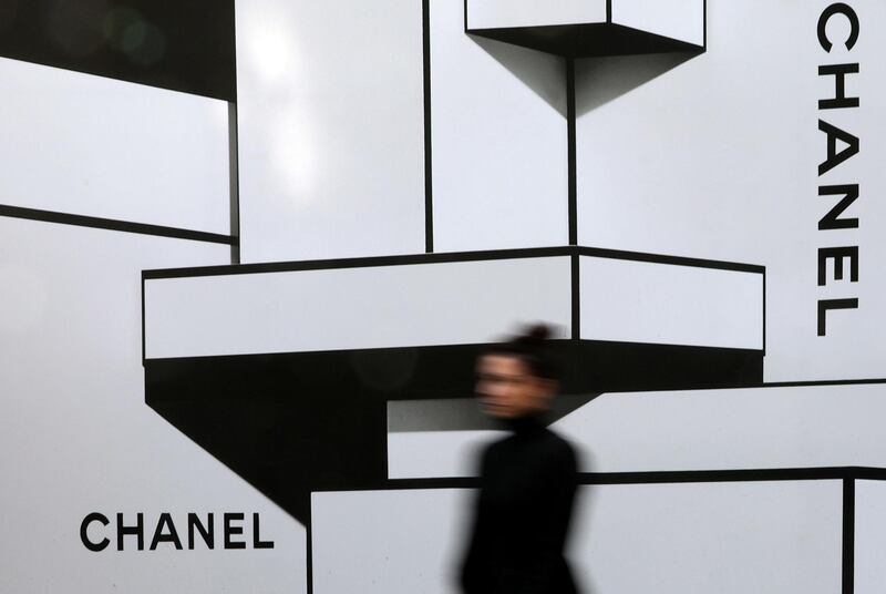 FILE PHOTO: A woman walks past a wall with logos of French luxury goods maker Chanel in Nice, France, February 22, 2017.    REUTERS/Eric Gaillard/File Photo