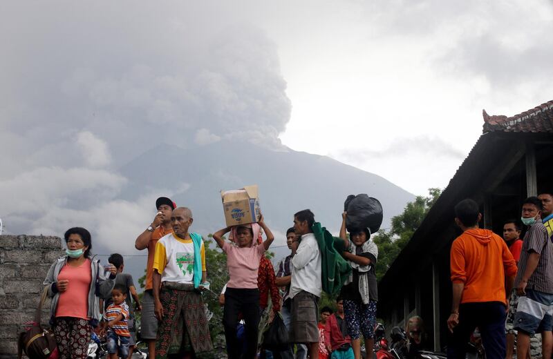 Villagers carry their belongings during an evacuation following the eruption of Mount Agung, seen in the background, in Karangasem, Indonesia. Firdia Lisnawati / AP Photo