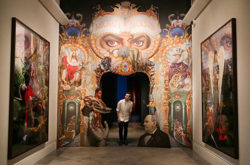 A gallery assistant poses next to an artwork entitled ’The King of Pop’ (C) by US artist Mark Ryden, on display during a photocall to promote the exhibition: 'Michael Jackson: On The Wall' at the National Portrait Gallery in central London on June 27, 2018. The exhibition is set to run from June 28 to October 21, 2018. / AFP / Daniel LEAL-OLIVAS
