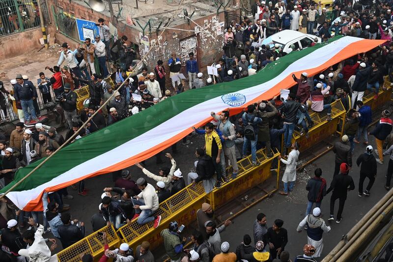 Protesters stand with a large Indian flag by the Jama Masjid mosque at a demonstration against India’s new citizenship law in New Delhi on December 20, 2019. AFP / Money SHARMA