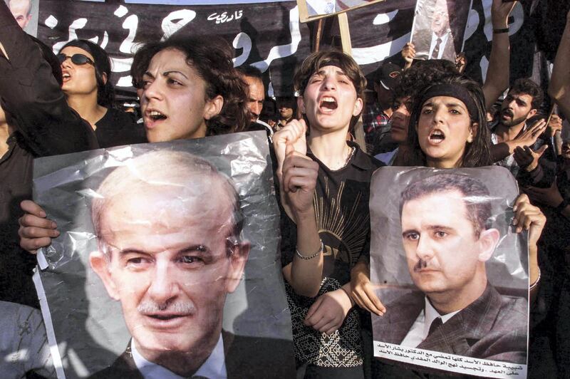 (FILES) In this file photo taken on June 13, 2000 Syrians, holding pictures of their late president Hafez al-Assad and his son and apparent heir, Bashar, mourn their leader in  the capital Damascus. - President Bashar al-Assad, whose family has ruled Syria for over half a century, faces an election this week meant to cement his image as the only hope for recovery in the war-battered country, analysts say. (Photo by RAMZI HAIDAR / AFP)