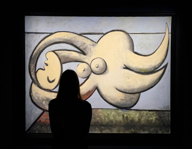 A woman poses in front of Pablo Picasso’s “Femme nue couchée" during the New York press preview on May 6, 2022, of Sotheby's Macklowe Collection spring auction.  (Photo by TIMOTHY A.  CLARY  /  AFP)  /  RESTRICTED TO EDITORIAL USE - MANDATORY MENTION OF THE ARTIST UPON PUBLICATION - TO ILLUSTRATE THE EVENT AS SPECIFIED IN THE CAPTION