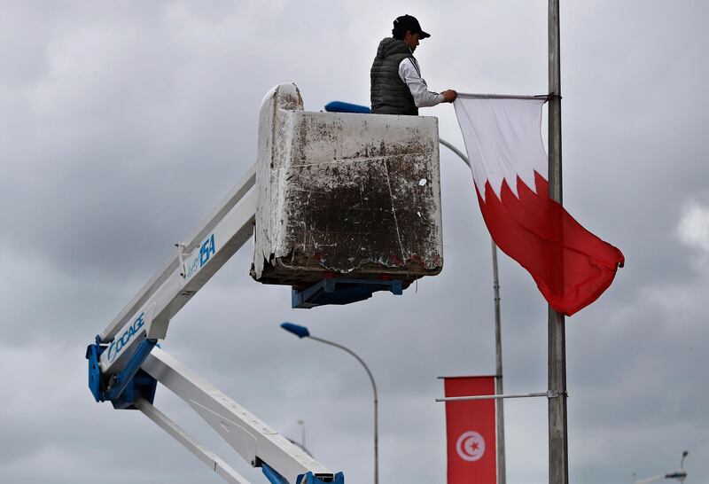 A worker sets the Bahraini flag near the conference center where the Arab League Summit will be held in Tunis. AP Photo