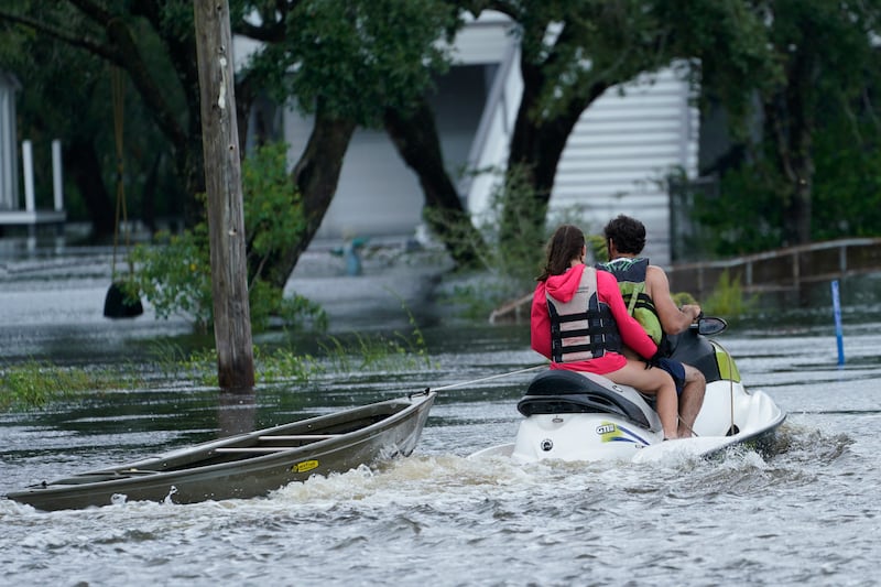 A resident on a jet ski tows a canoe to a flooded house in Bay Saint Louis. AP