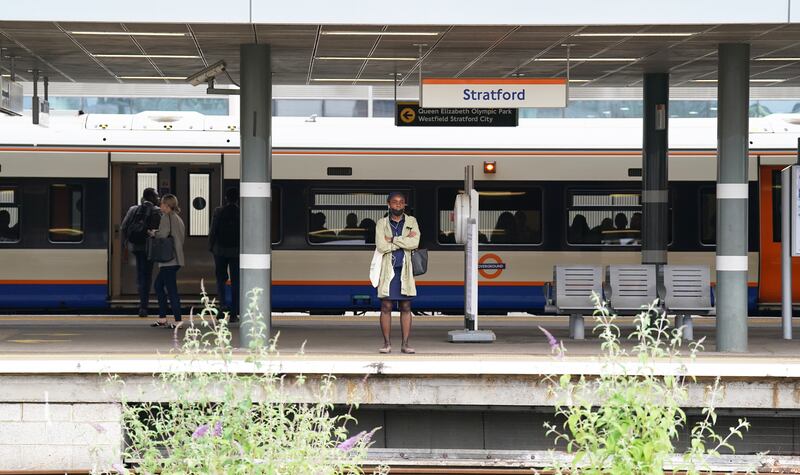 A passenger waits for a train at Stratford station in London. PA