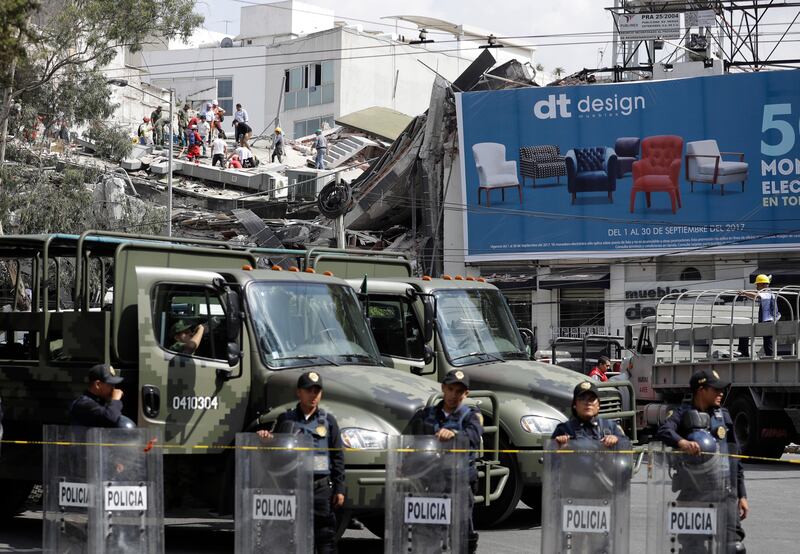 Police and military secure the area outside a building that collapsed, where people search for survivors, after an earthquake in the Roma neighbourhood of Mexico City. Rebecca Blackwell / AP Photo