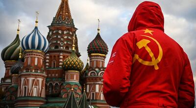 TOPSHOT - A man wearing a red jacket with a hammer and sickle symbol depicturing the Soviet national flag walks along the Red Square in front of St. Basil cathedral in Moscow on November 6, 2020.  / AFP / Alexander NEMENOV
