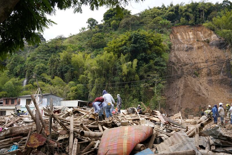 Residents remove debris after a landslide caused by heavy rain killed at least 14 people and injured dozens more in Pereira, Colombia. Reuters