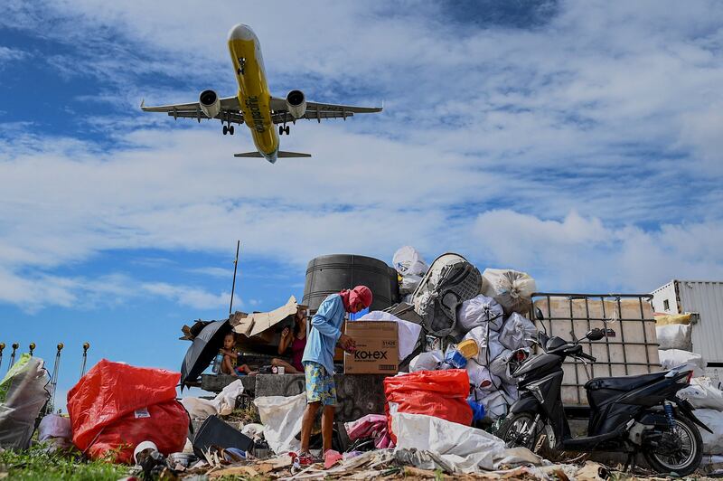 A Cebu Pacific aircraft flies by as a man collects rubbish in Paranaque, Metro Manila. AFP