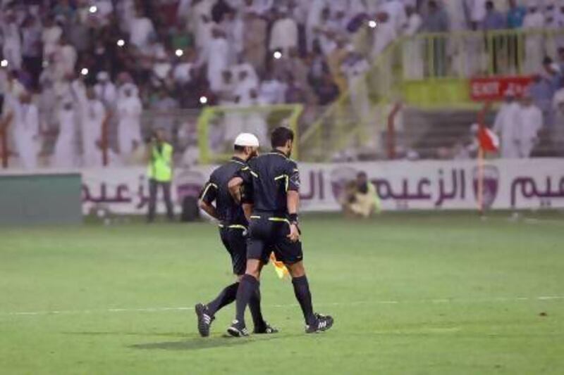 Referee’s assistant Mohammed Al Mehairi, left, is led from the field by referee Hamad Al Sheikh Hashmi on Saturday night.