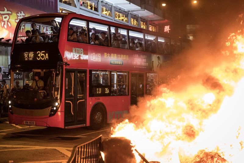 Passengers look out from a bus at a  burning barricade lit by pro-democracy protesters during a protest gathering in front of Mong Kok police station in Hong Kong, China. Getty