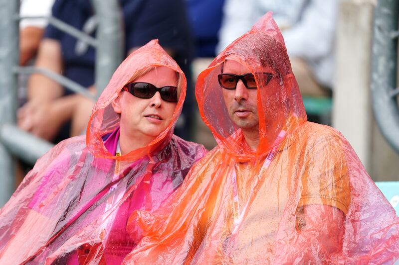Spectators keep themselves dry during the fifth Ashes Test  at The Kia Oval in London