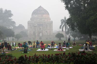(FILES) In this file photo taken on October 30, 2018 Indian yoga enthusiasts practice yoga in Lodhi Gardens amid heavy smog conditions in New Delhi. Residents of the Indian capital New Delhi lose on average ten years off their life expectancy due to the catastrophic effect of the city's air pollution, compared to their expected life longevity if they were breathing healthy air, according to a study published by the University of Chicago on November 19. / AFP / Dominique FAGET
