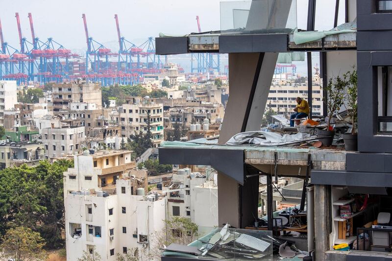 A man sits between debris inside his house damaged by Tuesday's explosion in the seaport of Beirut, Lebanon. AP Photo