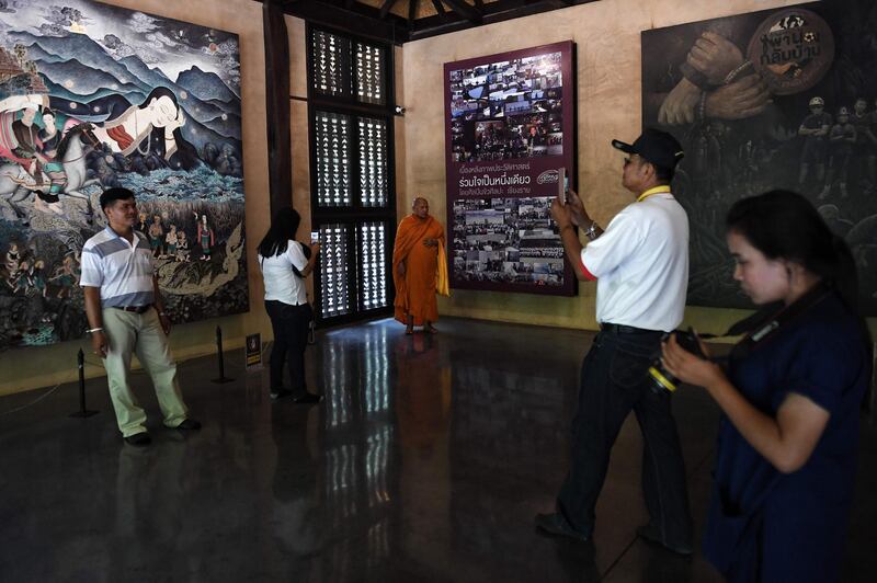 Visitors take photos in front of artwork illustrating the rescue of the 12 boys.  AFP