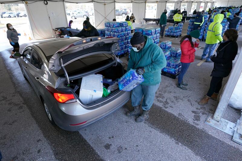 Water is loaded into the trunk of a car at a City of Houston water distribution site Friday, Feb. 19, 2021, in Houston. The drive-thru stadium location was setup to provide bottled water to individuals who need water while the city remains on a boil water notice or because they lack water at home due to frozen or broken pipes. (AP Photo/David J. Phillip)