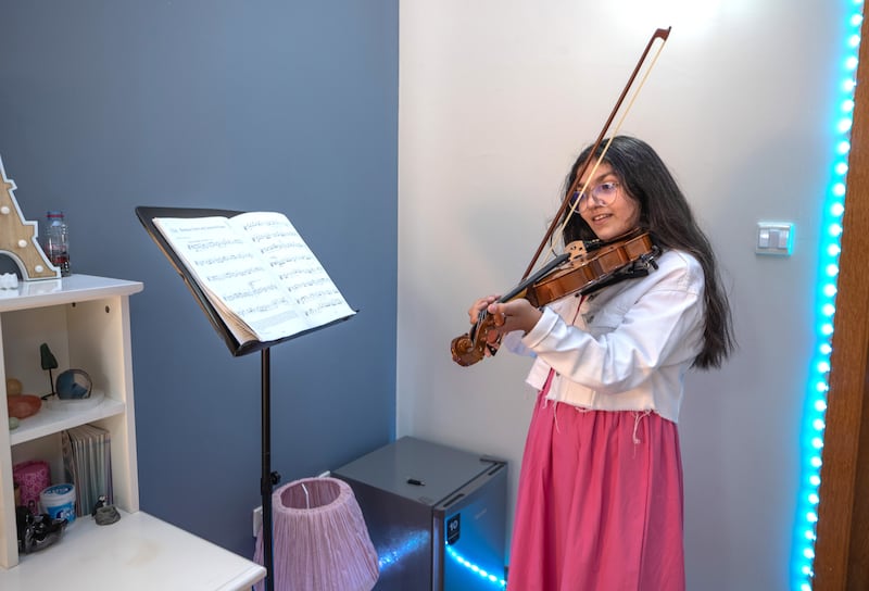 Celina, 11, plays the violin in her room. 
